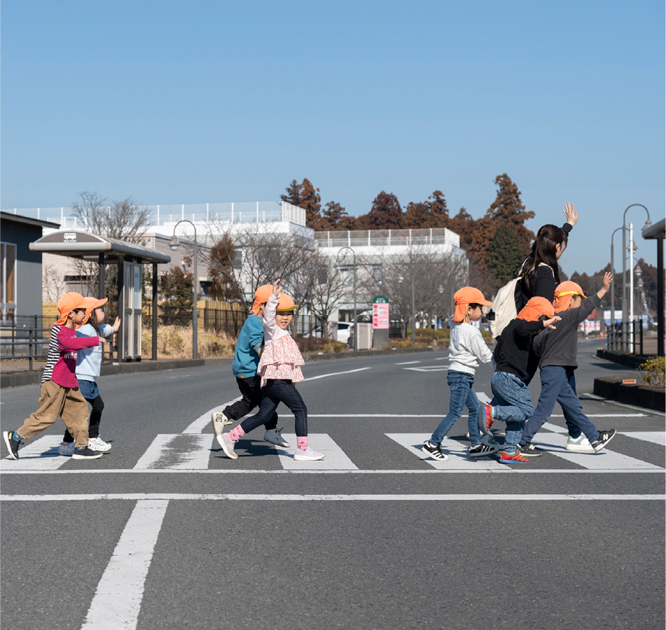 手を挙げて道路を渡る子供達